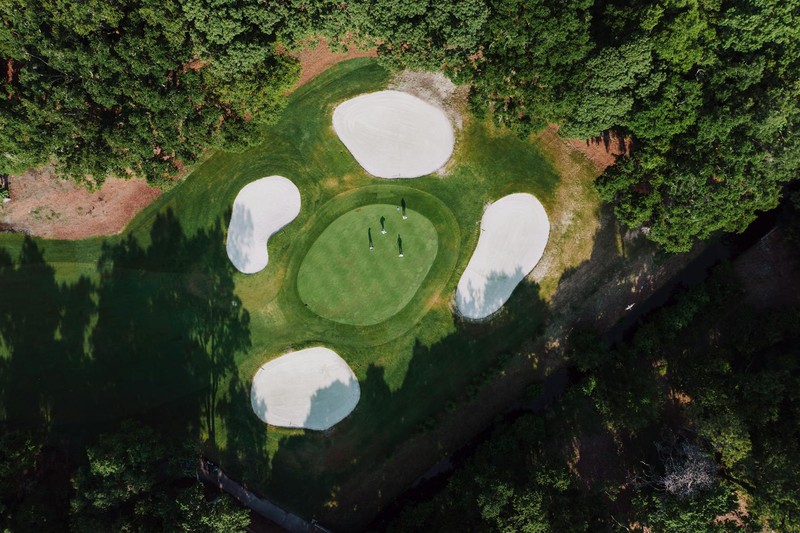 Aerial view of a lush green golf course with sand bunkers surrounded by forest on Hilton Head Island