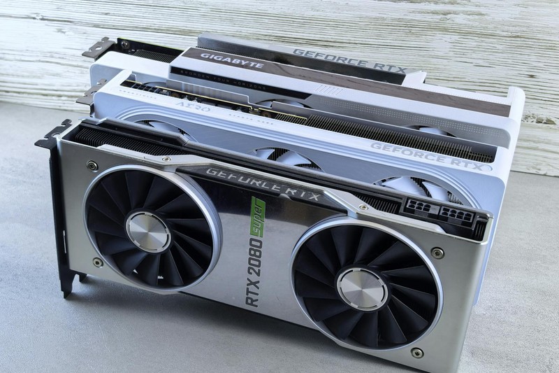 Three NVIDIA GeForce RTX graphics cards stacked on a surface, showing their dual-fan cooling design and branding