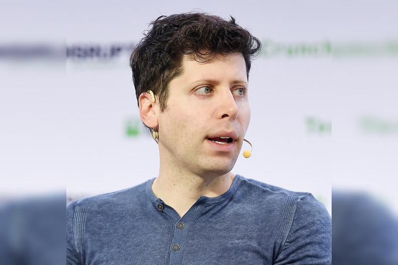 Sam Altman, CEO of OpenAI, speaking at a tech conference with an earpiece