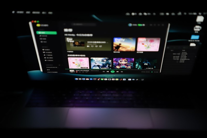 A laptop displaying the Steam Store interface with a grid of game thumbnails in a dimly lit room