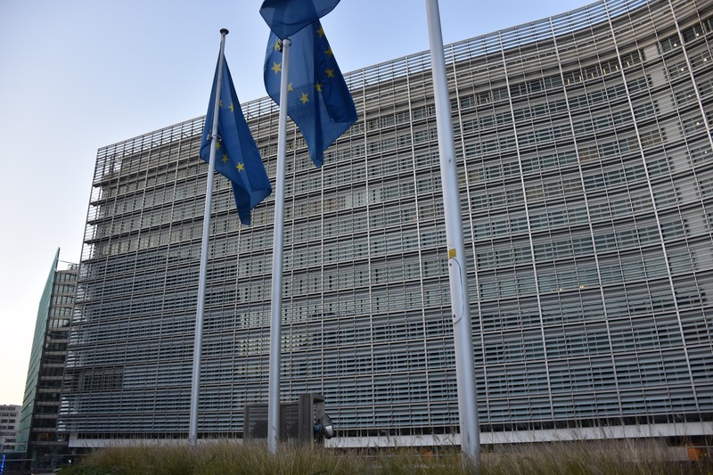 European Commission headquarters, the Berlaymont building in Brussels, Belgium, with EU flags in the foreground