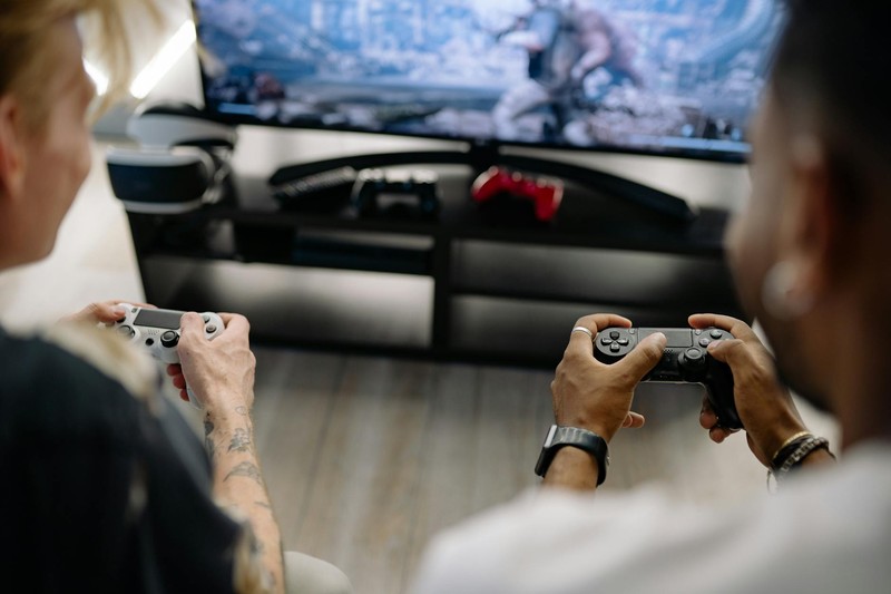 Two friends playing a co-op video game together with controllers in a living room