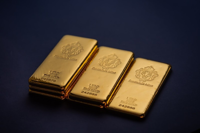 Three gold bullion bars arranged on a dark background