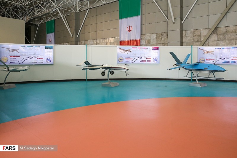 Iranian military UAVs on display at an aerospace exhibition with Iranian flags in the background