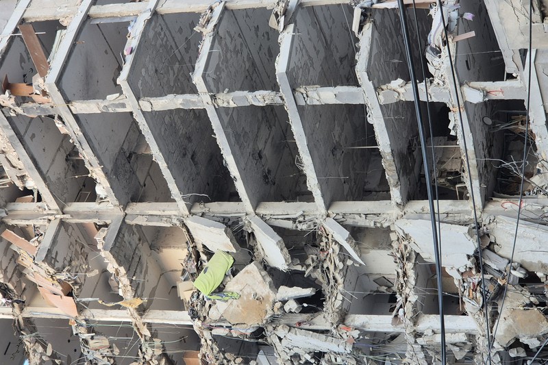 Heavily damaged multi-story building in Bat Yam, Israel, after an Iranian missile strike, with exposed concrete framework and rubble scattered around the structure.