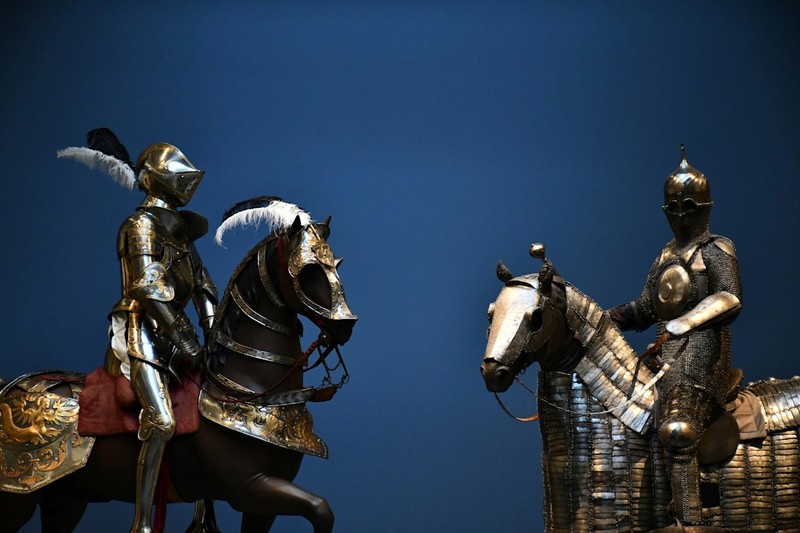 Two armored knights on horseback facing each other against a deep blue background