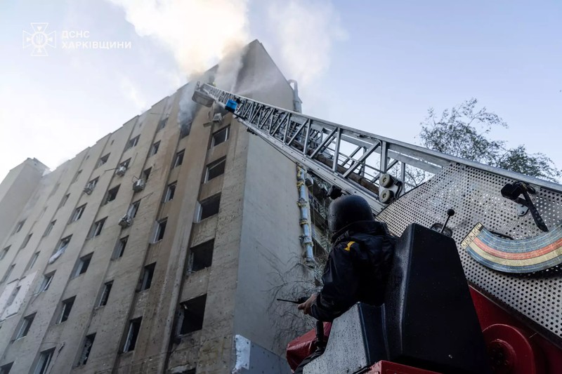 Aftermath of a Russian drone strike on a residential building in Kharkiv, with firefighters responding to smoke billowing from the structure