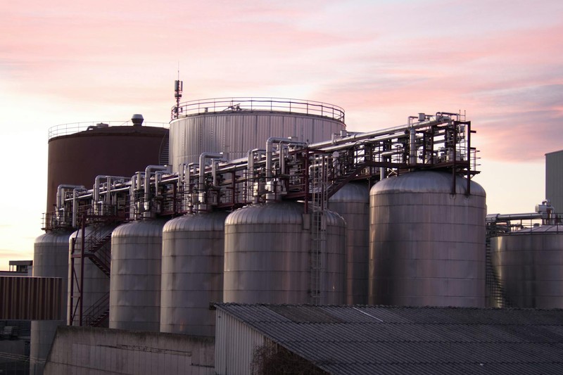 Industrial oil refinery with large storage tanks and piping at sunset