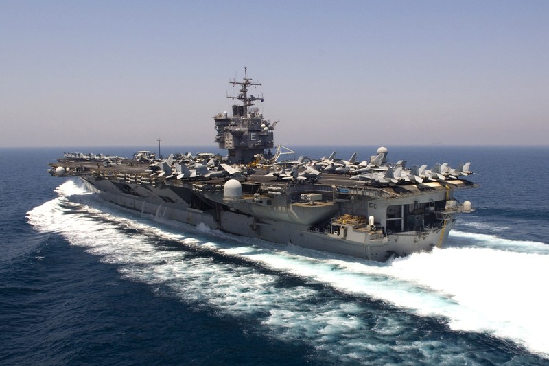 The aircraft carrier USS Enterprise transits the Persian Gulf during flight operations, with dozens of aircraft parked on the flight deck