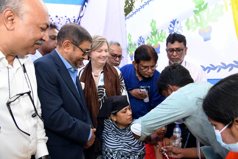 Bangladesh's Health Minister observes as a healthcare worker administers a vaccine to a child during the launch of the Emergency Measles-Rubella Vaccination Program