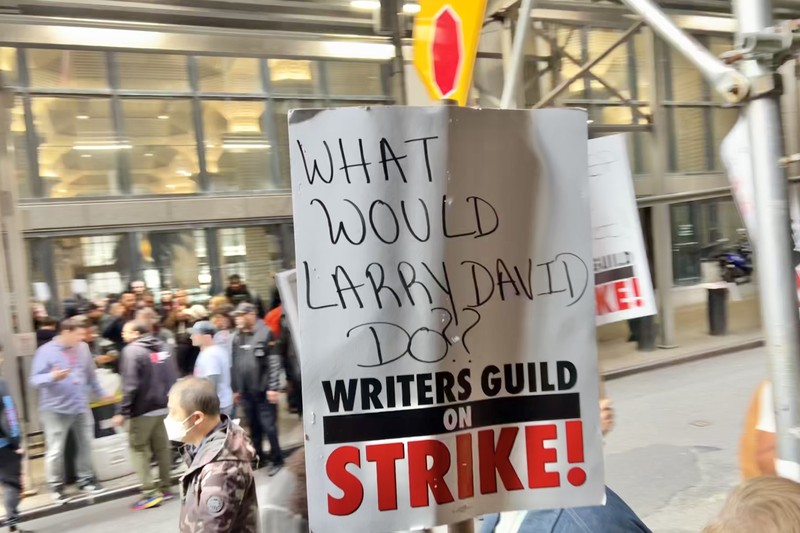 Writers Guild strike picket line with protest signs on a city street