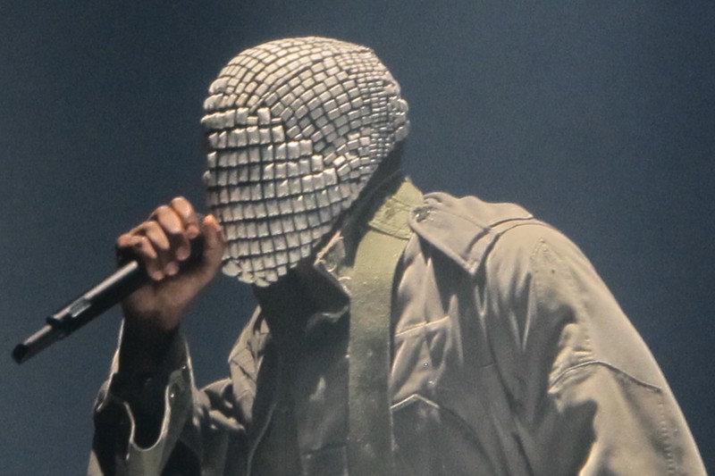 Kanye West performing on stage wearing a reflective tiled mask during the Yeezus Tour
