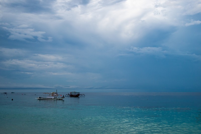 Fishing boats on the calm waters of the Lombok Strait under cloudy skies