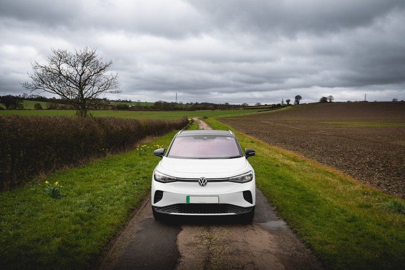 A white Volkswagen ID.4 electric SUV parked on a rural road under overcast skies