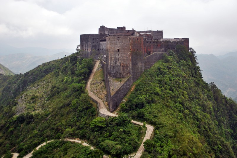Aerial view of Citadelle Laferrière fortress atop a lush green mountain in Haiti, with a winding path leading to the summit