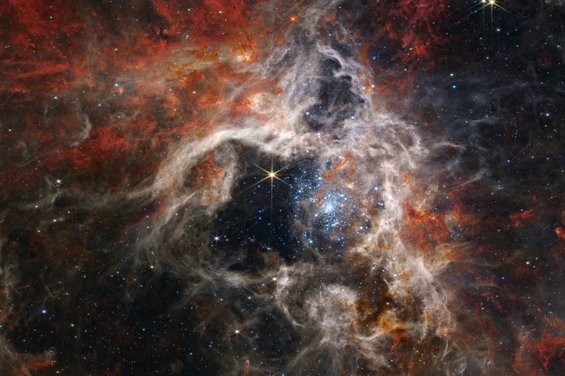 JWST image of the Tarantula Nebula revealing thousands of young stars and distant background galaxies