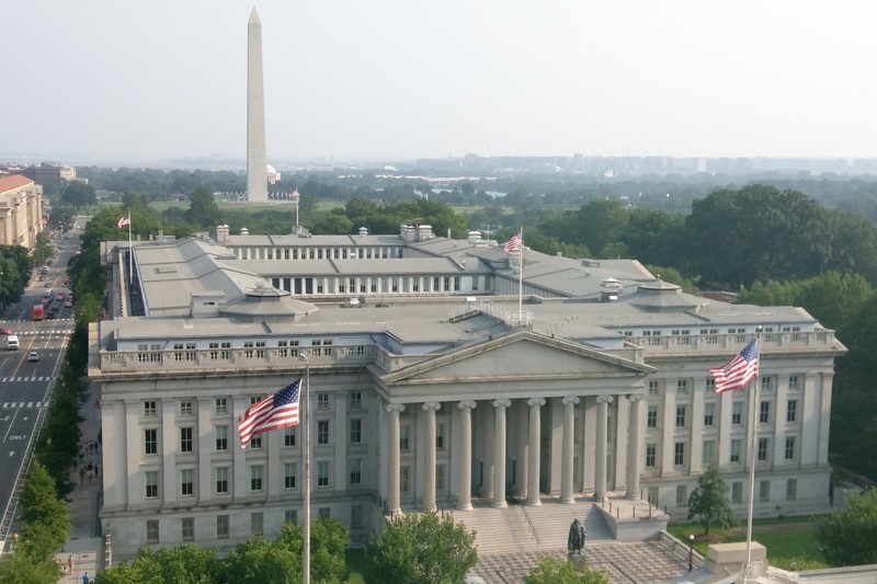 The U.S. Treasury Department building in Washington, D.C., with the Washington Monument visible in the background.