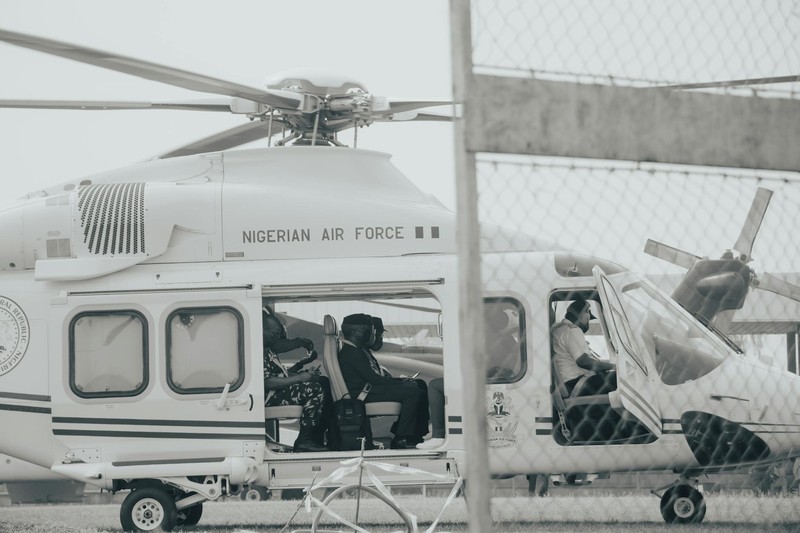 A Nigerian Air Force helicopter parked outdoors with uniformed personnel visible inside the open cabin