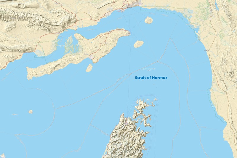 Topographic map of the Strait of Hormuz showing the narrow waterway between Iran and the Arabian Peninsula, with surrounding terrain, islands, and infrastructure