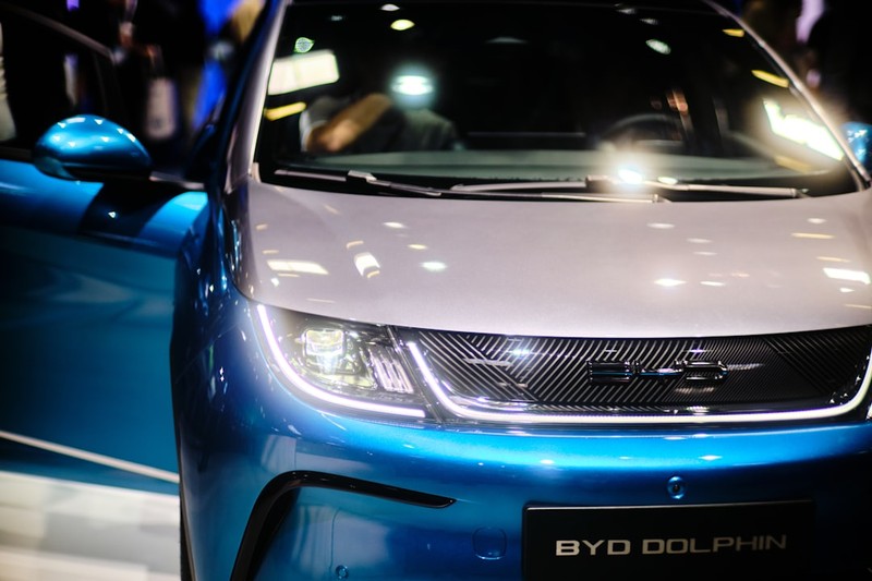 A blue and white BYD Dolphin electric car on display at an auto show