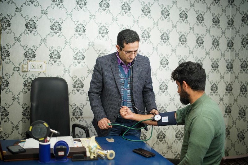 A doctor wearing a stethoscope checks a patient's blood pressure during a medical consultation