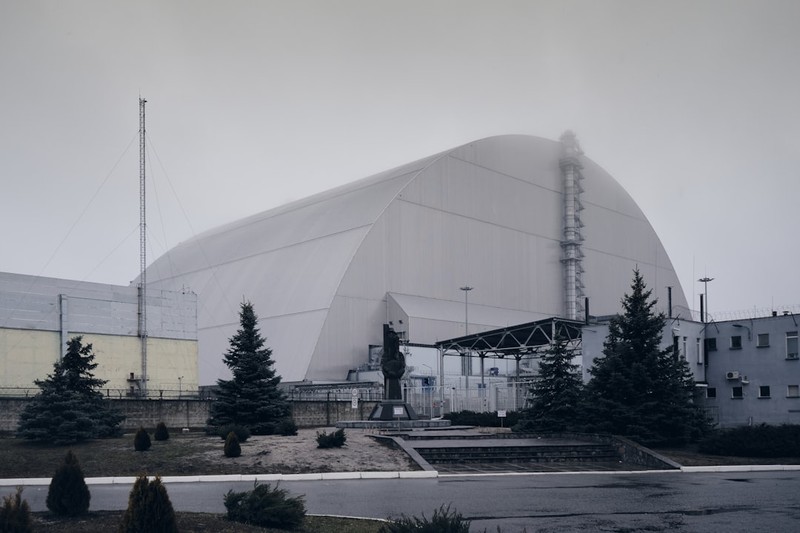 The Chernobyl New Safe Confinement arch-shaped containment structure looming over the nuclear power plant site under an overcast sky