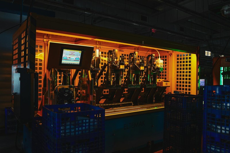 Complex industrial machinery illuminated by warm, dramatic lighting in a dark factory setting