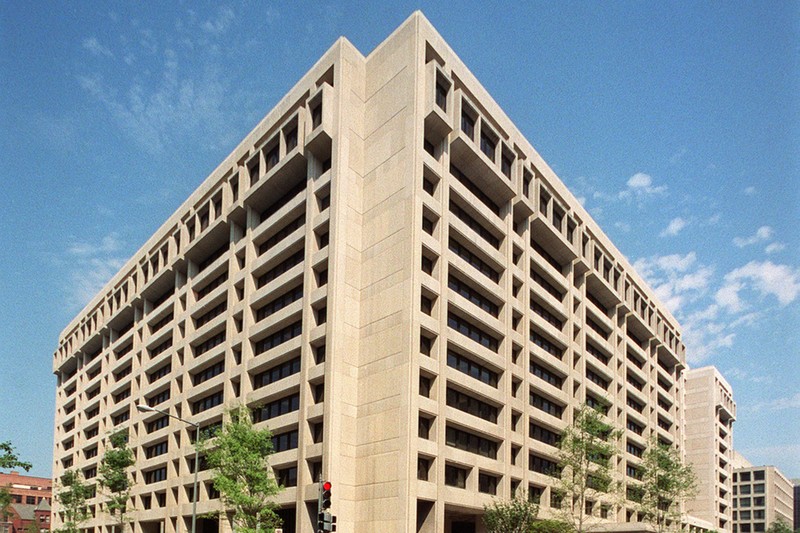 The International Monetary Fund headquarters building in Washington, DC, under a blue sky with scattered clouds