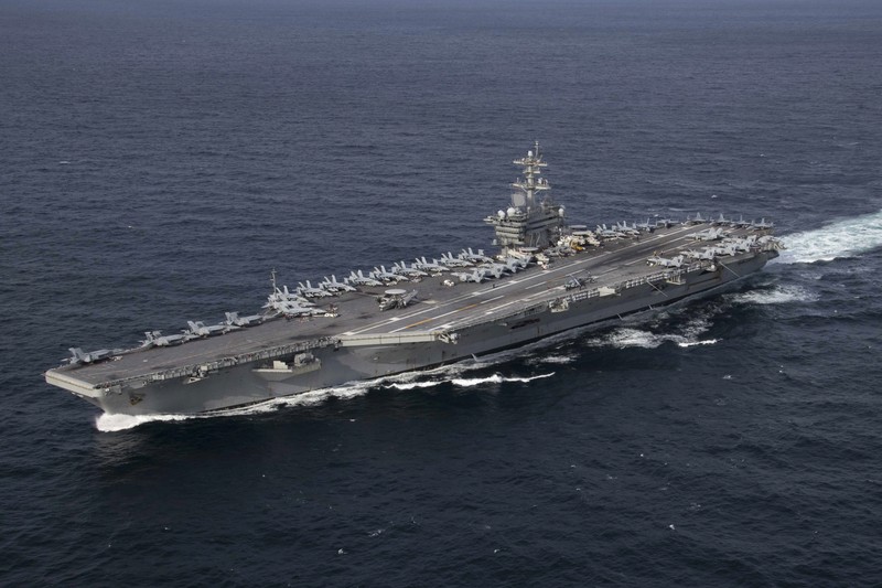 The USS Abraham Lincoln (CVN-72) aircraft carrier underway at sea with aircraft parked on the flight deck, leaving a white wake in the open ocean.