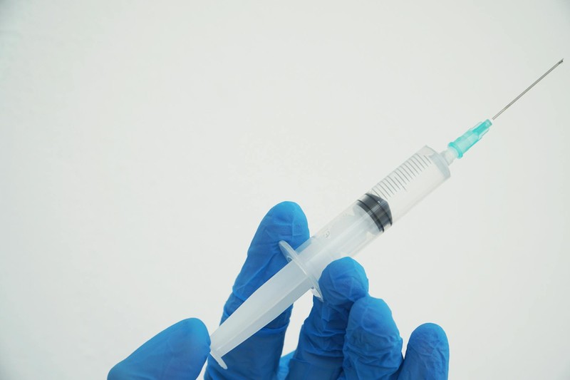 A gloved hand holding a medical syringe against a white background