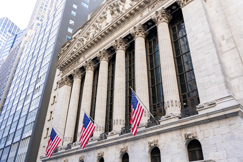 The neoclassical facade of the New York Stock Exchange with American flags hanging from the building