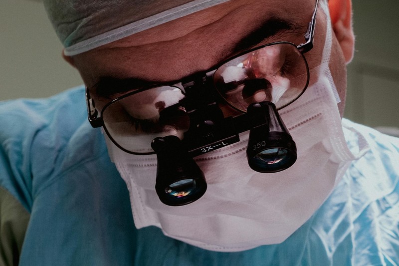 Close-up of a surgeon wearing surgical mask and magnification loupes in an operating room