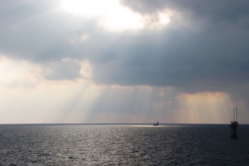 The Strait of Hormuz near Bandar Abbas, Iran, with dramatic clouds over calm waters and a distant vessel on the horizon