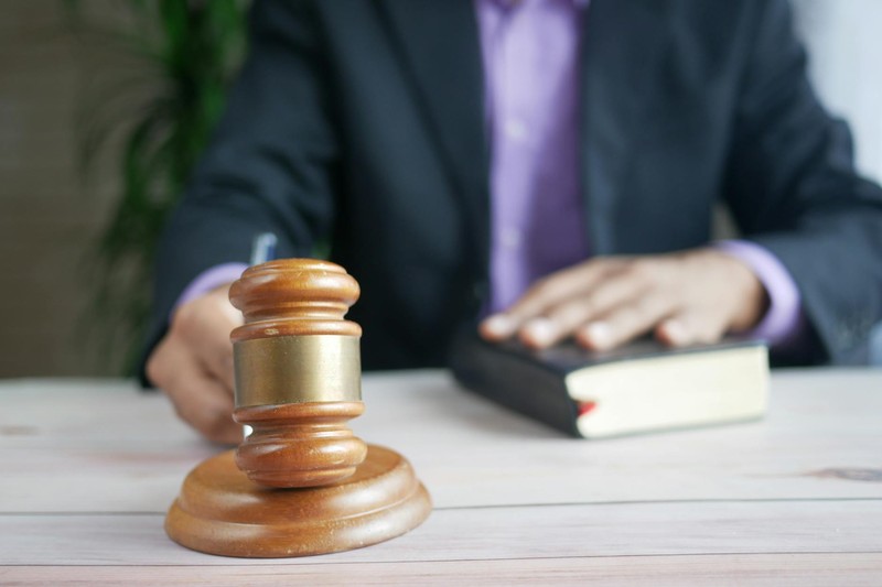 A wooden gavel and legal book on a judge's bench symbolize judicial authority