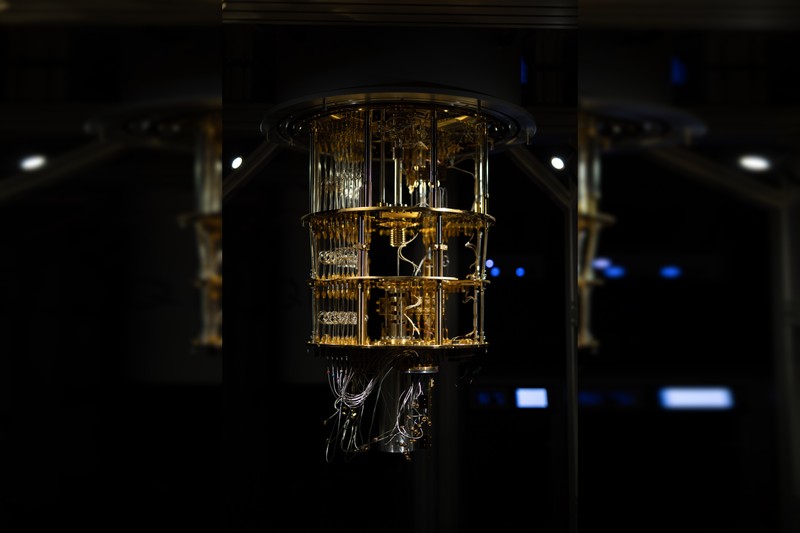 A large quantum computer with intricate gold-colored metallic framework and complex wiring, photographed from below against a dark background