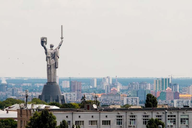The Motherland Monument towers over Kyiv's cityscape under a gray overcast sky