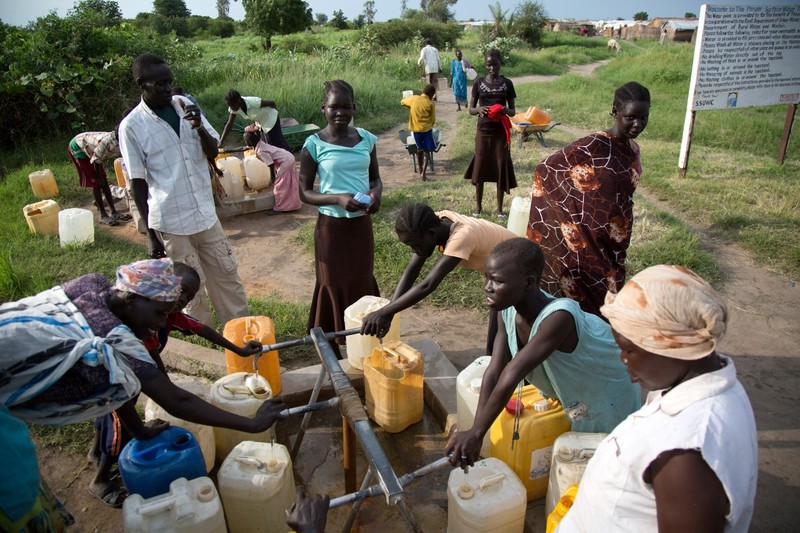 Women and children collect water from a hand pump at a displaced persons camp in Renk, South Sudan