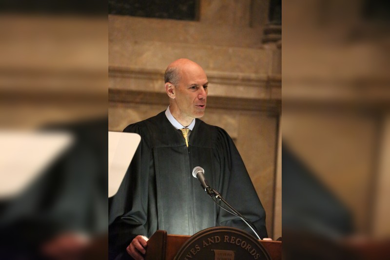 Judge James E. Boasberg speaking in a black judicial robe inside the National Archives Rotunda