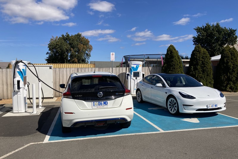 Two white electric vehicles plugged in and charging at an Evie Networks fast charging station in Campbell Town, Tasmania