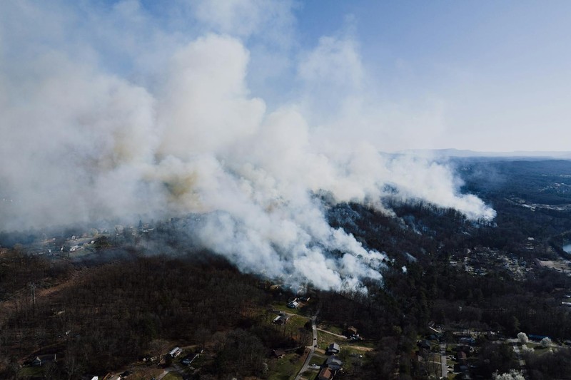 Aerial drone view of thick smoke billowing from a wildfire over a residential neighborhood and forested area in Georgia