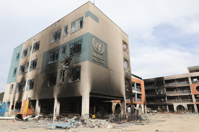 A heavily damaged UNRWA building in Gaza with fire-blackened walls and surrounding rubble