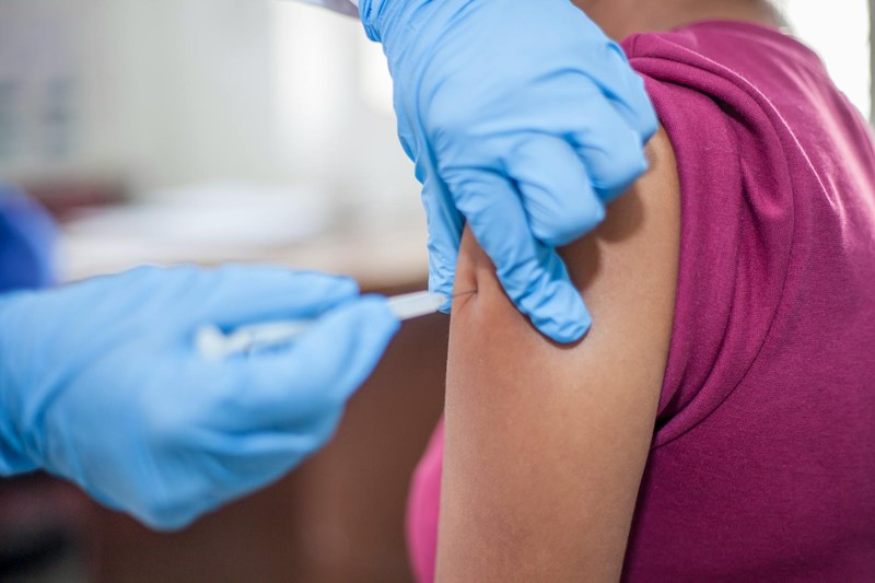 Close-up of a healthcare professional in blue gloves administering a vaccine injection into a patient's arm