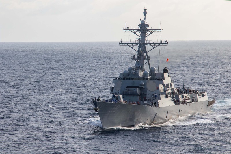A U.S. Navy guided-missile destroyer transits the Indian Ocean, cutting through calm gray waters under an overcast sky.