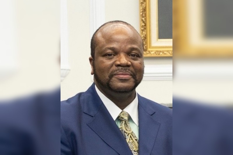An African leader in formal attire seated in an official setting with ornate gold-framed artwork
