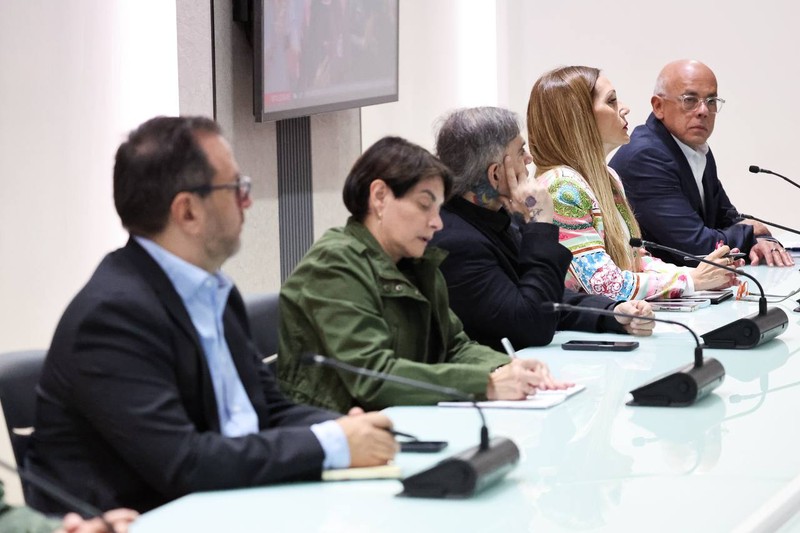 Government officials seated at a formal meeting table with microphones in Venezuela following the capture of President Nicolás Maduro