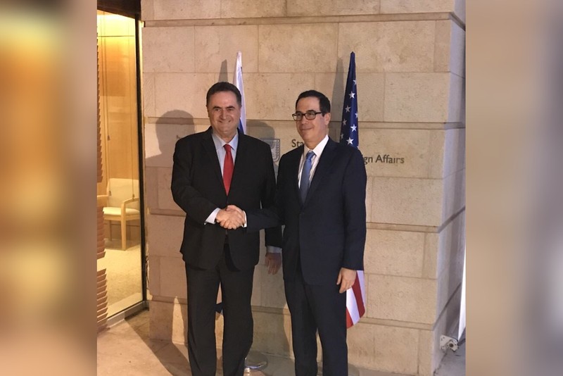 U.S. and Israeli officials shake hands with both nations' flags displayed behind them