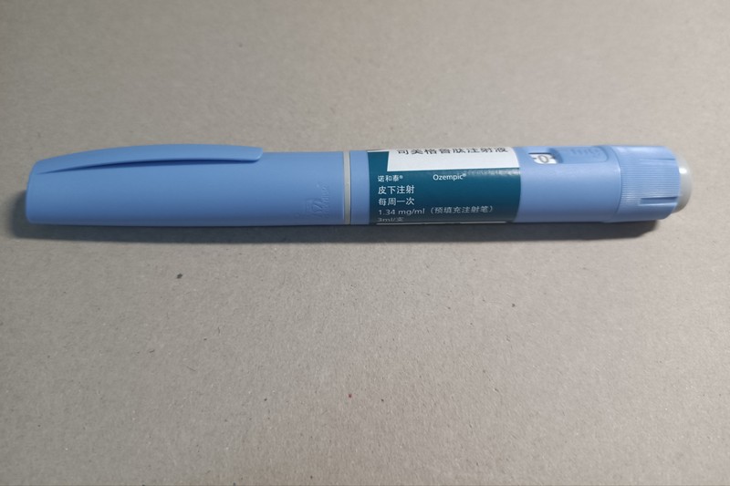 A light blue Ozempic semaglutide injection pen on a plain background