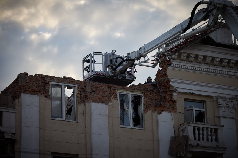 Damaged five-story apartment building in Dnipro, Ukraine, with a fire truck ladder extended toward the partially collapsed upper section after a massive Russian missile attack.