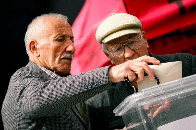 Two senior adults casting their votes at a polling station ballot box