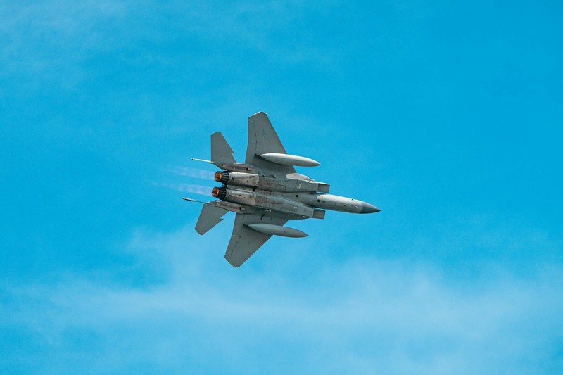 A military fighter jet soars through a clear blue sky, showcasing aerial power and advanced military technology.